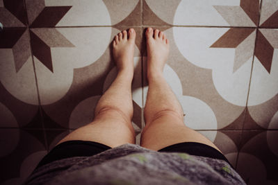 Low section of woman lying on tiled floor