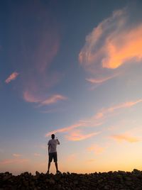 Man standing on land against sky during sunset