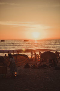 People on beach against sky during sunset