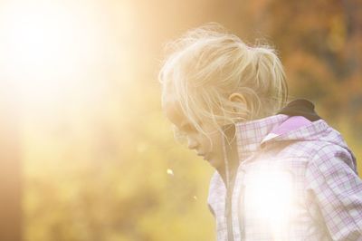 Cute girl with blond hair playing in park during sunny day