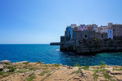 Buildings sea against clear blue sky