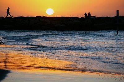 Silhouette of people at beach during sunset