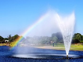 Scenic view of rainbow over fountain against sky