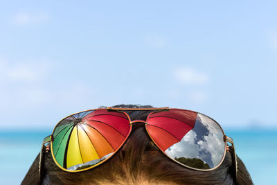 Reflection of umbrella falling on sunglasses on woman head