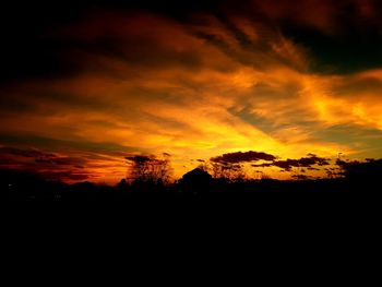 Silhouette landscape against dramatic sky during sunset