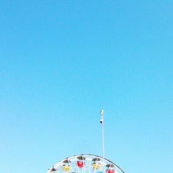 Low angle view of carousel against clear blue sky
