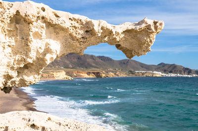 Scenic view of rocks on sea shore against sky