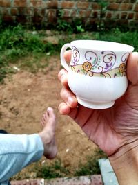 Cropped hand of woman holding cup outdoors