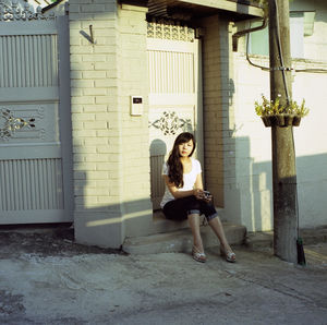 Young woman sitting in front of building