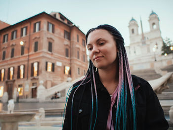 Portrait of beautiful woman standing against buildings in city