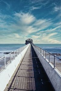 View of boardwalk leading towards sea against sky