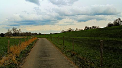 Scenic view of grassy field against cloudy sky