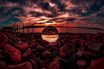 Digital composite image of rocks on beach against sky during sunset