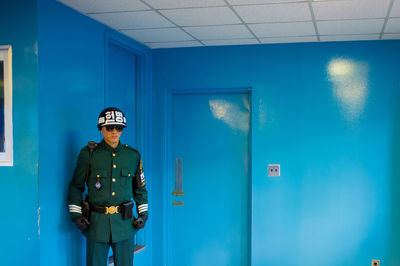 Man standing against blue wall