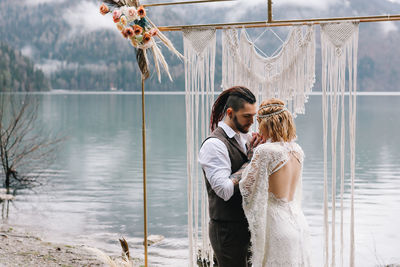 A loving married couple the bride and groom in suits celebrate wedding near the mountains and water