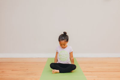 Full length of girl sitting on hardwood floor