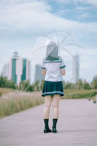 Rear view of woman with umbrella standing in rain