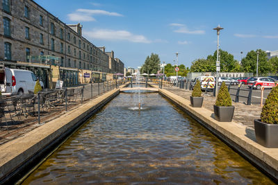 Bridge over canal in city against sky