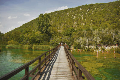 Footbridge over lake against sky