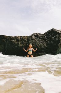 Full length of shirtless man in sea against sky