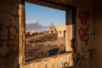 Abandoned abades church seen through windows of old houses at sunrise.