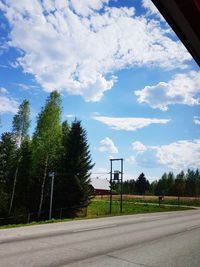 Empty road amidst trees against sky
