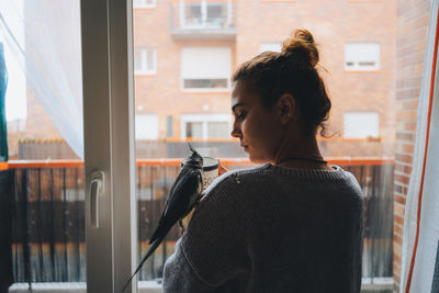 Portrait of young woman looking through window