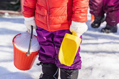 Midsection of person holding bucket with snow