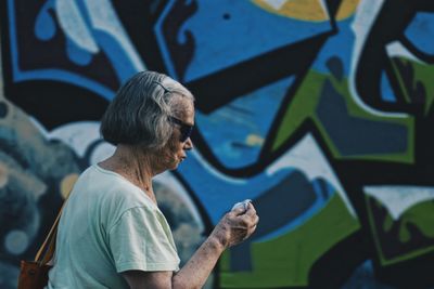 Rear view of woman standing against graffiti wall