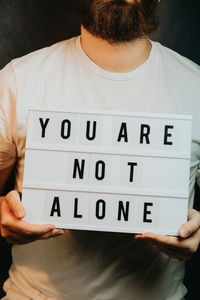 Midsection of man holding text against black background