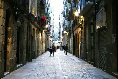 Woman walking on alley amidst buildings