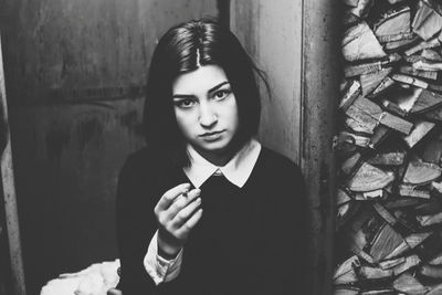 Portrait of young woman smoking cigarette at home