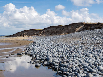 Surface level of stones on beach against sky