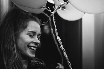 Close-up of happy young woman holding balloons at home