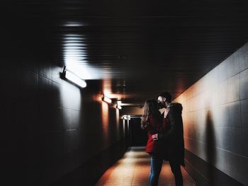 Full length of man standing in illuminated corridor