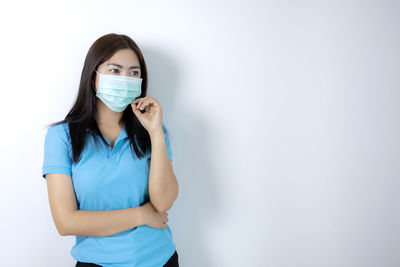 Portrait of a young woman standing against white background