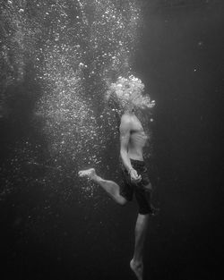 Man wearing short jeans swimming and floating in clear water