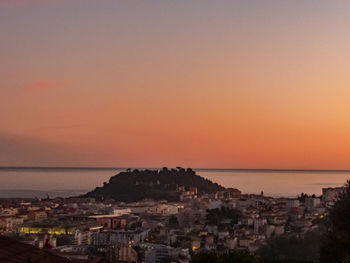 High angle view of townscape by sea against sky during sunset