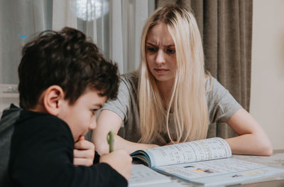 Mom and son are doing homework. sister helps brother solve math. home schooling. high quality photo