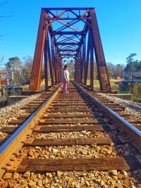 Woman standing on railroad tracks against clear sky