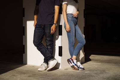 Low section of man and woman standing on umbrella