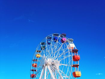 Low angle view of ferris wheel against blue sky