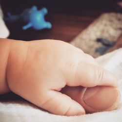 Close-up of baby holding mother thumb