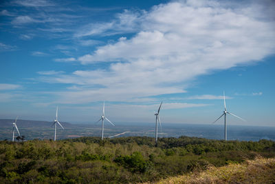 Wind turbines on field against sky