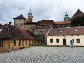 Old castle by houses against sky