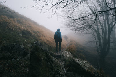 Rear view of man standing on mountain against sky