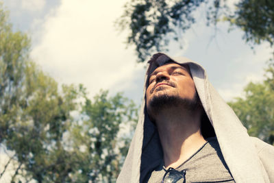 Low angle view of man looking up against trees