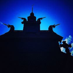Low angle view of silhouette building against blue sky