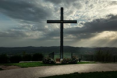 Cross on field against sky