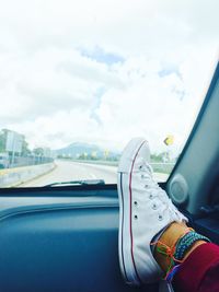 Low section of person in car against sky